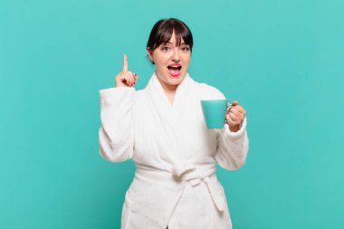 Bornoz giyen genç bir kadın bir fikri fark ettikten sonra mutlu ve heyecanlı bir dahi gibi hissediyor. Neşeli bir şekilde parmak kaldırıyor.!