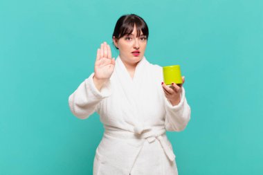 Bornoz giymiş genç bir kadın ciddi, sert, hoşnutsuz ve kızgın görünüyor.