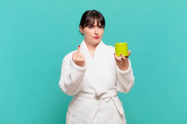 Bornoz giyen genç bir kadın kızgın, sinirli, asi ve agresif, orta parmağını sallıyor, karşı koyuyor.