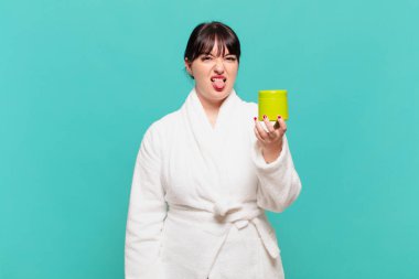 Bornoz giyen genç bir kadın tiksinti ve tedirginlik duyuyor, dilini dışarı çıkarıyor, iğrenç ve iğrenç bir şeyden hoşlanmıyor.