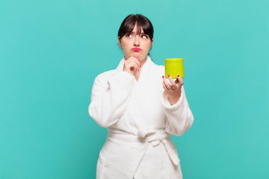 Bornoz giymiş genç bir kadın. Düşünüyor, kuşkulu ve kafası karışık. Farklı seçenekleri var.