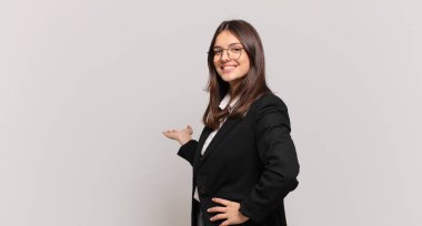 Genç iş kadını kendini mutlu ve neşeli hissediyor, gülümsüyor ve seni hoş karşılıyor, seni dostça bir jestle içeri davet ediyor.