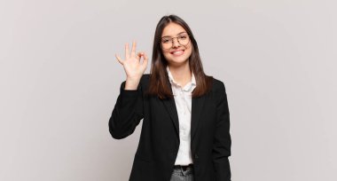 Genç iş kadını kendini mutlu, rahat ve tatmin olmuş hissediyor. Onayını iyi bir hareketle gösteriyor. Gülümsüyor.