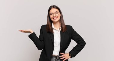 Genç iş kadını gülümsüyor, kendinden emin, başarılı ve mutlu hissediyor, fotokopi alanında fikir veya konsept gösteriyor.