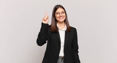 Genç iş kadını mutlu bir şekilde gülümsüyor, tek eliyle boşluğu dolduruyor.