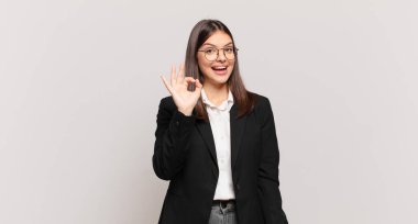 Genç iş kadını kendini başarılı ve tatmin olmuş hissediyor, ağzı açık gülümsüyor, elle imza atıyor.