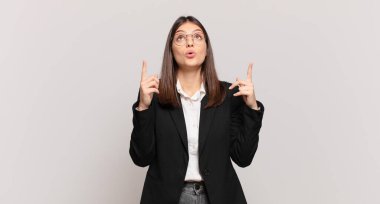 Genç iş kadını şaşkınlık ve açık sözlü hissediyor. Şok olmuş ve şaşırmış bir bakışla yukarı bakıyor.