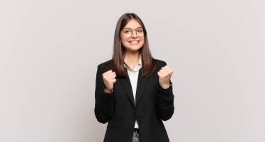 Genç iş kadını zaferle bağırıyor, gülüyor, mutlu ve heyecanlı hissediyor başarıyı kutlarken.