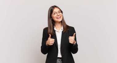 Genç iş kadını mutlu, pozitif, kendinden emin ve başarılı bir şekilde gülümsüyor.