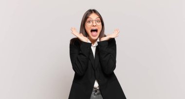 Genç bir iş kadını beklenmedik bir sürpriz yüzünden şaşkın, heyecanlı, gülen, şaşkın ve mutlu hissediyor.