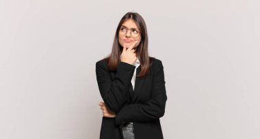 Genç iş kadını düşünüyor, kuşkulu ve şaşkın hissediyor, farklı seçeneklerle, hangi kararı vereceğini merak ediyor.