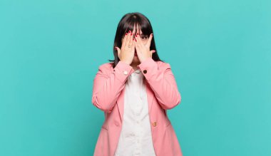 Genç iş kadını korkmuş ya da utanmış hissediyor. Gözleri yarı kapalı ya da ellerle dikizliyor ya da dikizliyor.