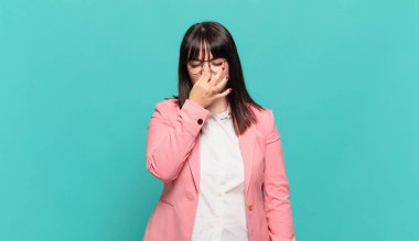 Genç iş kadını iğreniyor, kötü ve nahoş bir koku duymamak için burnunu tutuyor.