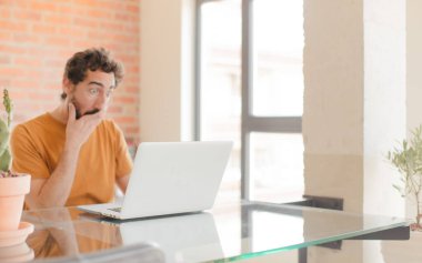 Evde dizüstü bilgisayarla çalışan sakallı genç bir adam.