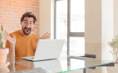 Evde dizüstü bilgisayarla çalışan sakallı genç bir adam.