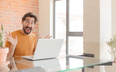 Genç sakallı adam mutlu, heyecanlı, şaşırmış ya da şok olmuş hissediyor. İnanılmaz bir şeye gülümsüyor ve hayrete düşüyor. Ve bir dizüstü bilgisayarla çalışıyor.