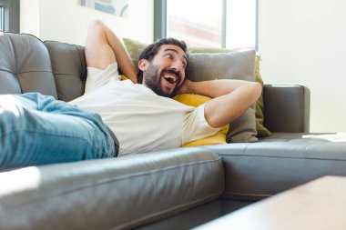 Genç sakallı adam kanepede dinleniyor.