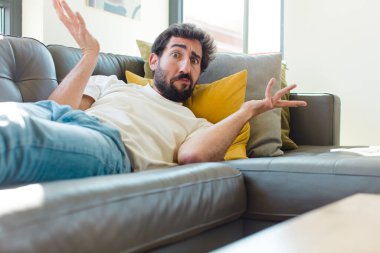 Genç sakallı adam kanepede dinleniyor.