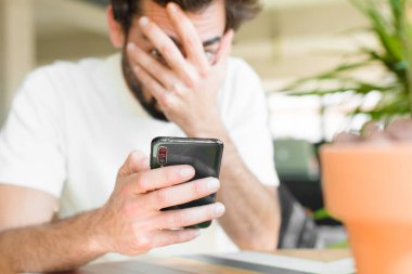 Evde akıllı telefonu olan sakallı genç bir adam.