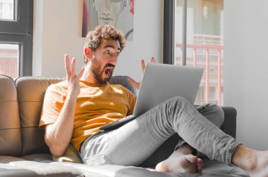 Genç sakallı adam elleri havada bağırıyor, öfkeli, sinirli, stresli ve dizüstü bilgisayar konsepti yüzünden üzgün.