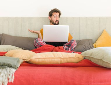 Genç sakallı adam şaşkın ve şaşkın hissediyor, şüpheci, farklı seçenekleri tartıyor veya komik bir ifadeyle seçiyor.