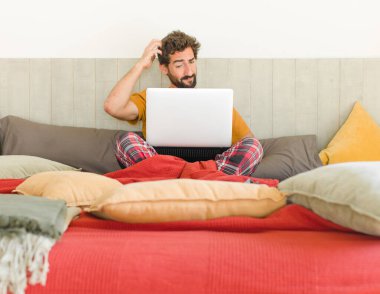 Genç sakallı adam şaşkın ve kafası karışmış hissediyor, başını kaşıyor ve yan tarafa bakıyor.