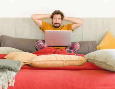 Genç sakallı adam kendini stresli, endişeli ya da korkmuş hissediyor. Elleri başının üstünde, hatayla panikliyor.