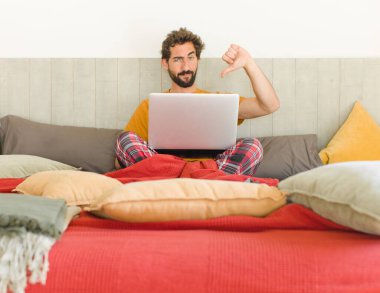 Genç sakallı adam sinirli, sinirli, hayal kırıklığına uğramış ya da canı sıkkın, ciddi bir bakışla başparmağını kaldırıyor.