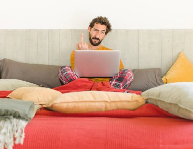 Genç sakallı adam kızgın, sinirli, asi ve agresif hissediyor, orta parmağını hareket ettiriyor, karşı koyuyor.