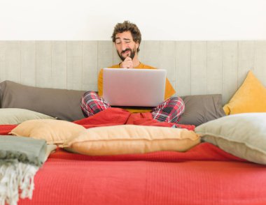 Genç sakallı adam düşünüyor, kuşkulu ve şaşkın hissediyor, farklı seçeneklerle, hangi kararı vereceğini merak ediyor.