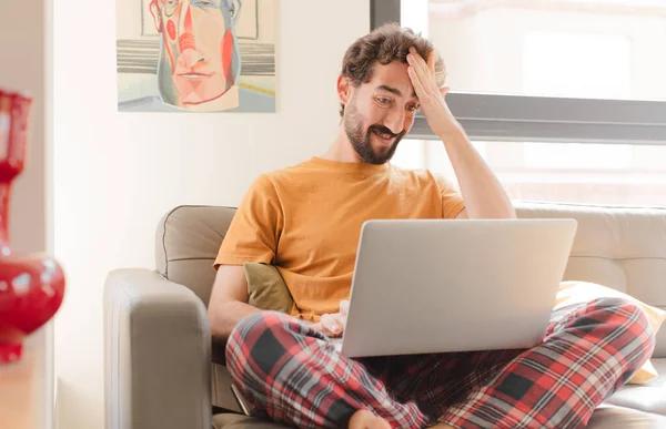 young bearded man on a couch with a laptop