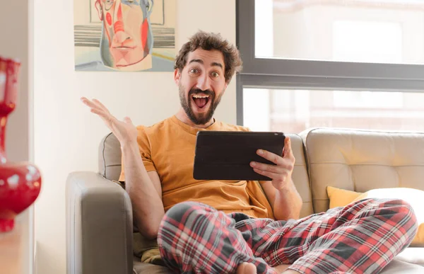 Kanepedeki sakallı genç adam Dokunmatik ekranlı tabletle