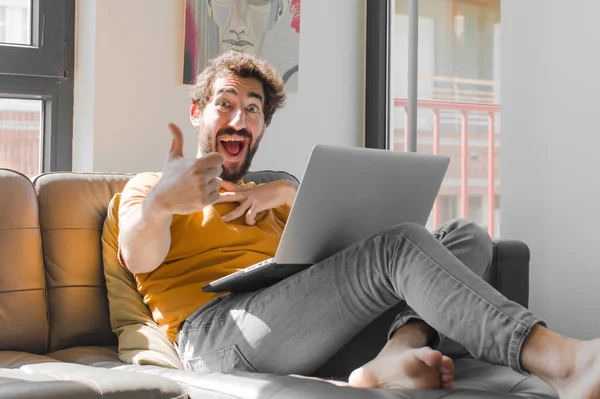 Genç sakallı adam gururlu, kaygısız, kendinden emin ve mutlu hissediyor. Dizüstü bilgisayarlı bir dizüstü bilgisayarla gülümsüyor.