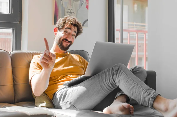 Genç sakallı adam gururla gülümsüyor ve gururla bir numaralı pozu veriyor. Dizüstü bilgisayarında dizüstü bilgisayarı olan bir lider gibi hissediyor.