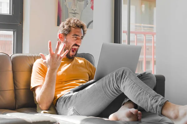 Genç sakallı adam sinirli, sinirli ve hayal kırıklığına uğramış görünüyor. Dizüstü bilgisayarda dizüstü bilgisayarla ne sorunun var? 