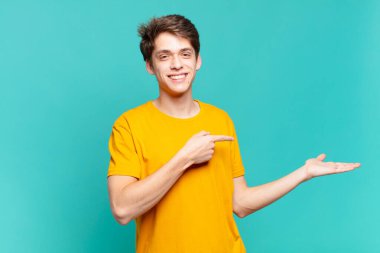 Genç çocuk gülümsüyor, mutlu, kaygısız ve tatmin olmuş hissediyor, fotokopi alanındaki konsepte veya fikre işaret ediyor.