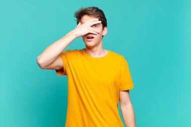 Delikanlı şok olmuş, korkmuş ya da korkmuş görünüyordu. Yüzü elle kaplıydı ve parmaklarının arasından bakıyordu.