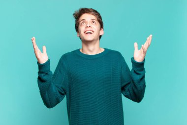 Genç çocuk kendini mutlu, şaşkın, şanslı ve şaşırmış hissediyor. Zaferi kutluyor. İki eli havada.