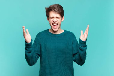 Genç çocuk öfkeyle bağırıyor, stresli hissediyor ve ellerini havaya kaldırıp neden ben diye bağırıyor.