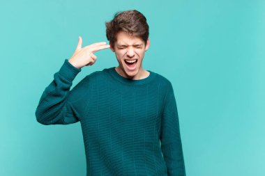 Genç çocuk mutsuz ve stresli görünüyor, intihar jesti elle silah işareti yapıyor, kafasını işaret ediyor.