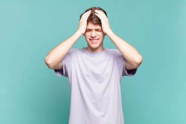 Delikanlı kendini stresli ve endişeli hissediyor. Depresyonda ve baş ağrısı yüzünden hayal kırıklığına uğramış. İki elini de başa kaldırıyor.