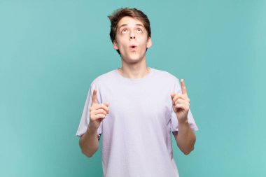 Delikanlı şaşkınlık ve şaşkınlık dolu bir bakışla yukarıyı işaret ediyor.