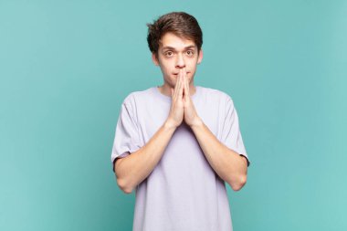 Genç çocuk mutlu ve heyecanlı, şaşırmış ve şaşırmış elleriyle ağzını kapatmış, tatlı bir ifadeyle kıkırdıyor.