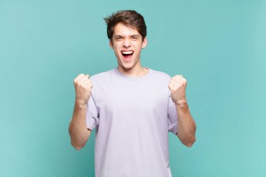 Genç bir çocuk öfkeli bir ifadeyle ya da yumruklarıyla başarıyı kutlarken agresif bir şekilde bağırıyor.