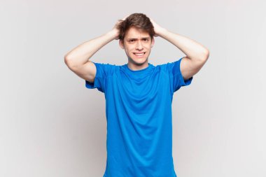 Genç çocuk kendini stresli, endişeli, endişeli ya da korkmuş hissediyor. Elleri başının üstünde, hatayla panikliyor.