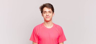 Genç çocuk pozitif ve kendinden emin gülümsüyor. Tatmin olmuş, arkadaş canlısı ve mutlu görünüyor.