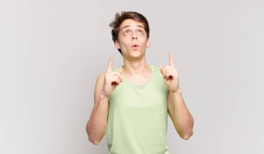Delikanlı şaşkınlık ve şaşkınlık dolu bir bakışla yukarıyı işaret ediyor.