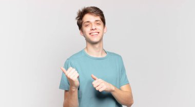 Genç çocuk neşeyle gülümsüyor ve tesadüfen fotokopi alanını işaret ediyor, mutlu ve tatmin olmuş hissediyor.