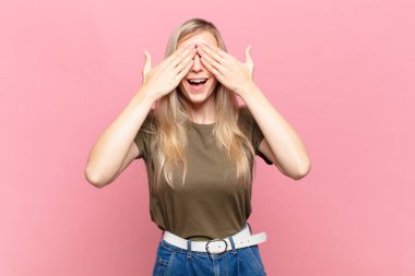 Genç sarışın güzel kadın gülümsüyor ve mutlu hissediyor, iki eliyle gözlerini kapatıyor ve inanılmaz bir sürpriz bekliyor.