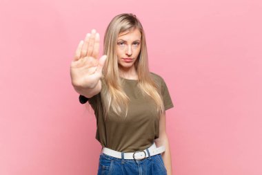 Genç sarışın güzel bir kadın ciddi, sert, hoşnutsuz ve kızgın görünüyor.